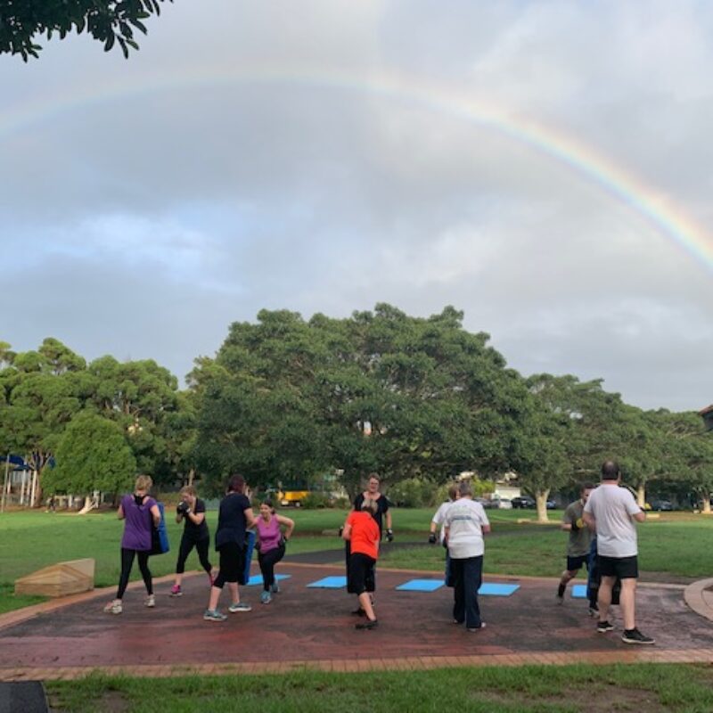 group exercising outdoors with rainbow